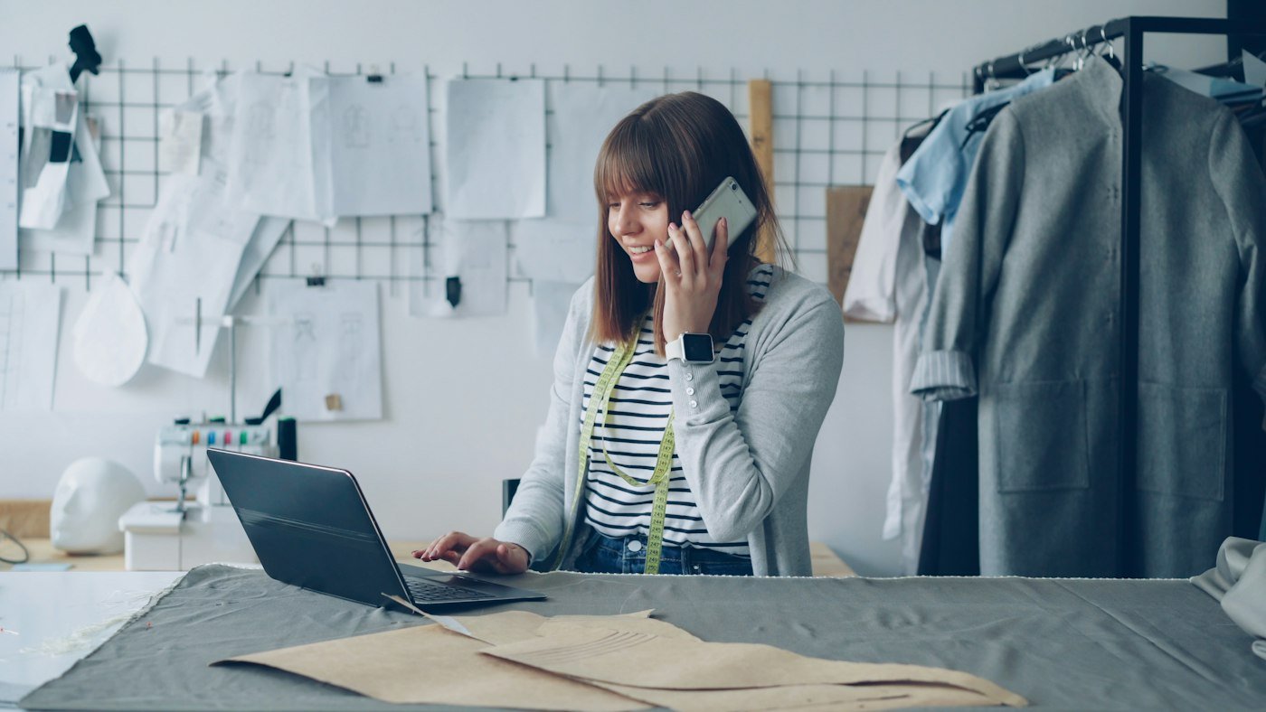 Entrepreneur talking on the phone with a client while reviewing digital marketing results on a laptop