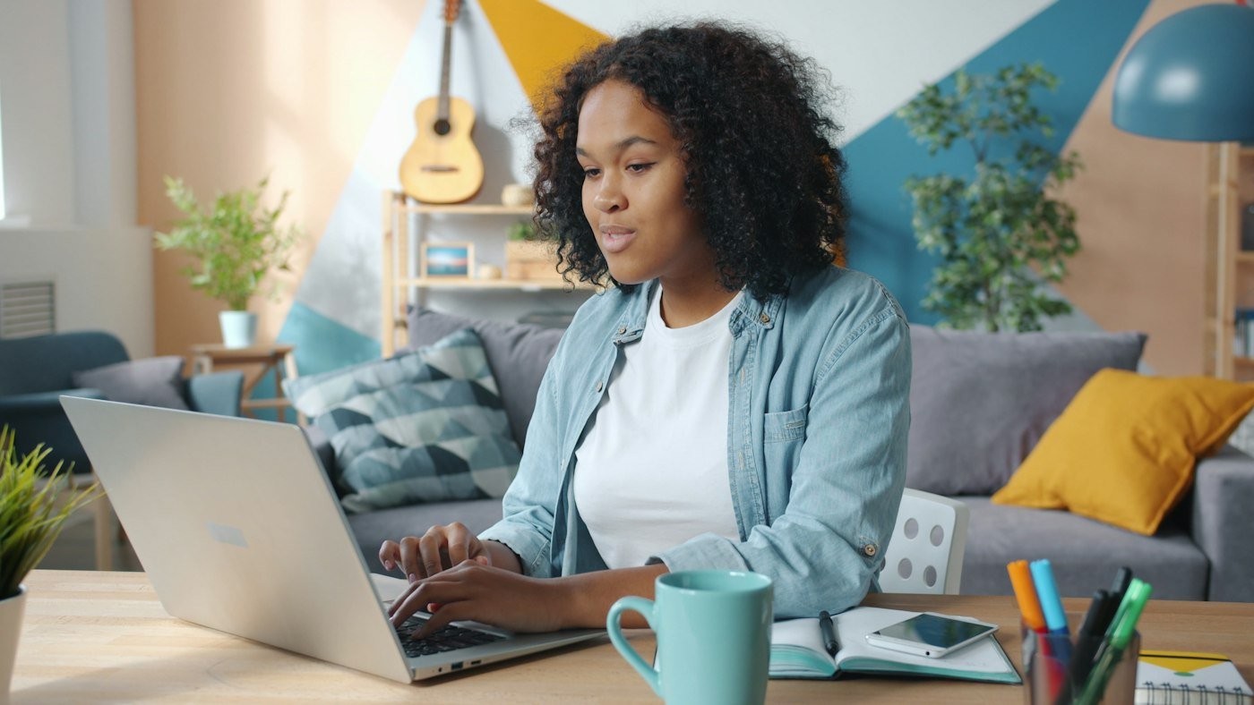 Woman working on a laptop at home, using automated workflows to save time